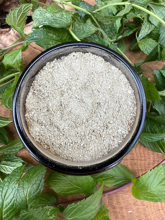 Jar of natural remineralizing tooth powder with peppermint leaves